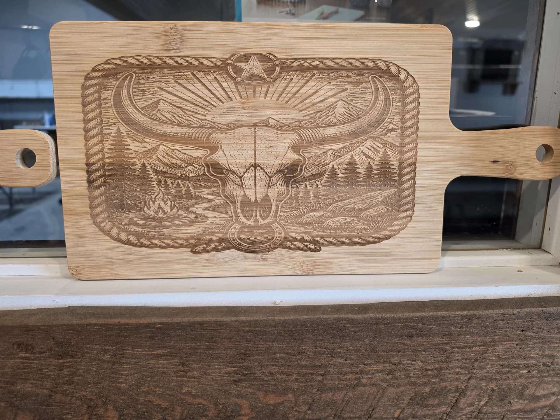 Bamboo paddle board laser engraved with a longhorn skull and mountains
