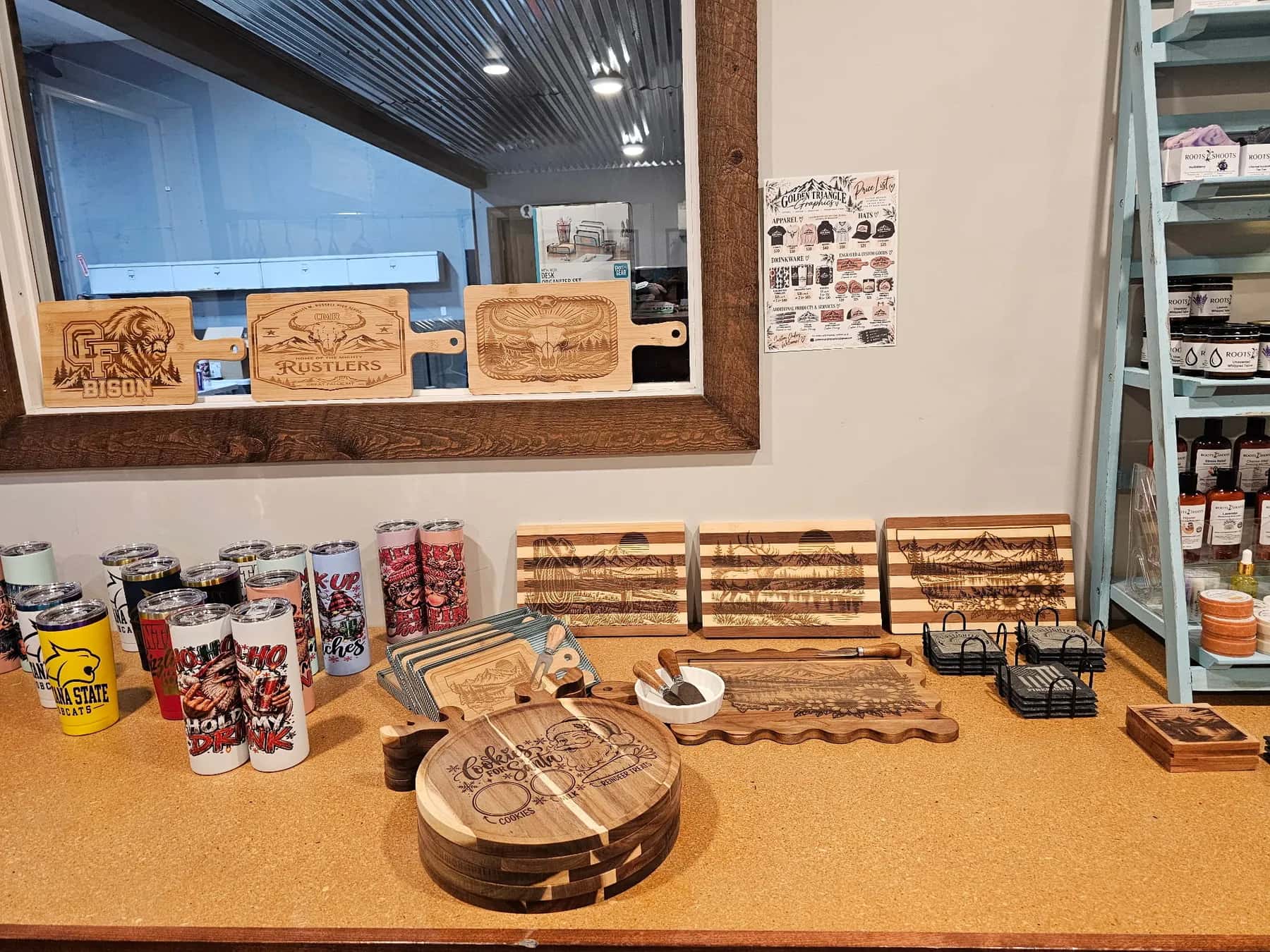 Laser engraved boards, coasters and tumblers on the counter in our shop, with the Bison and Rustlers boards in the window